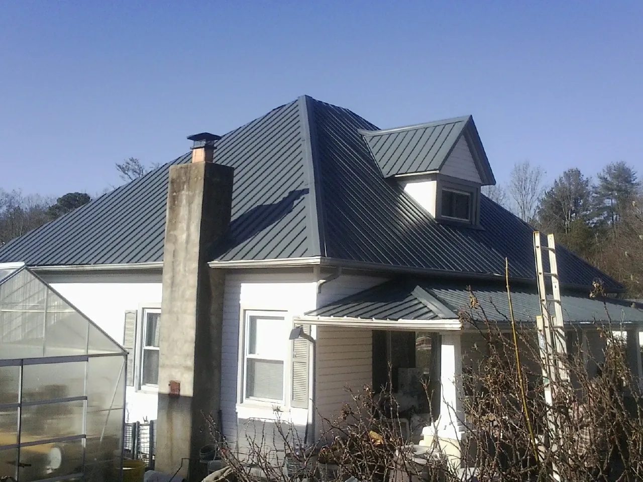 Dark blue standing seam metal roof on a white farmhouse with dormer — Slate & Tile Roof Repair by Roofing Brothers in Orangevale