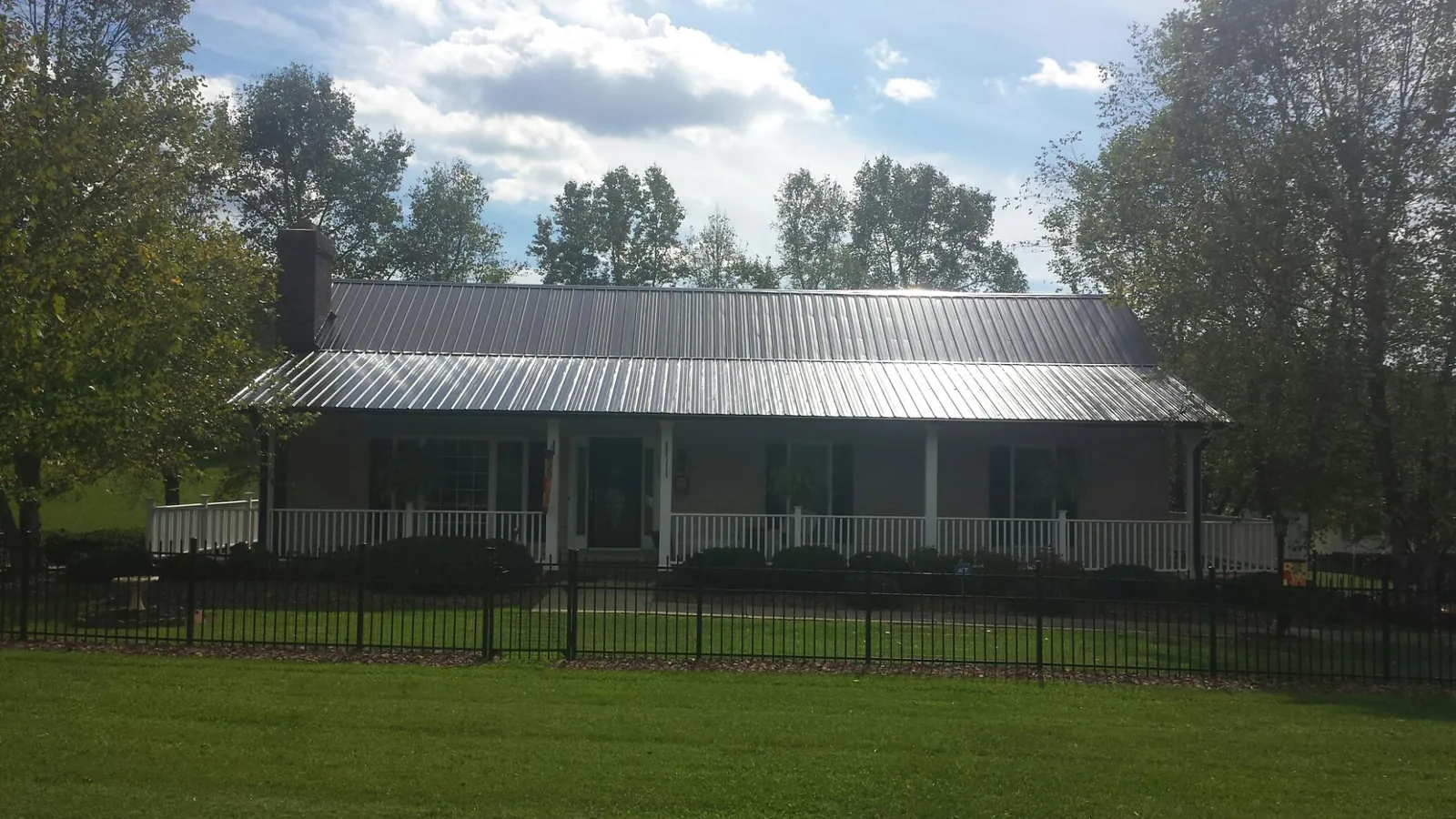 Gray metal roof on a brick ranch with a full width front porch — Gutter Guard Installation work by our crew in Orangevale
