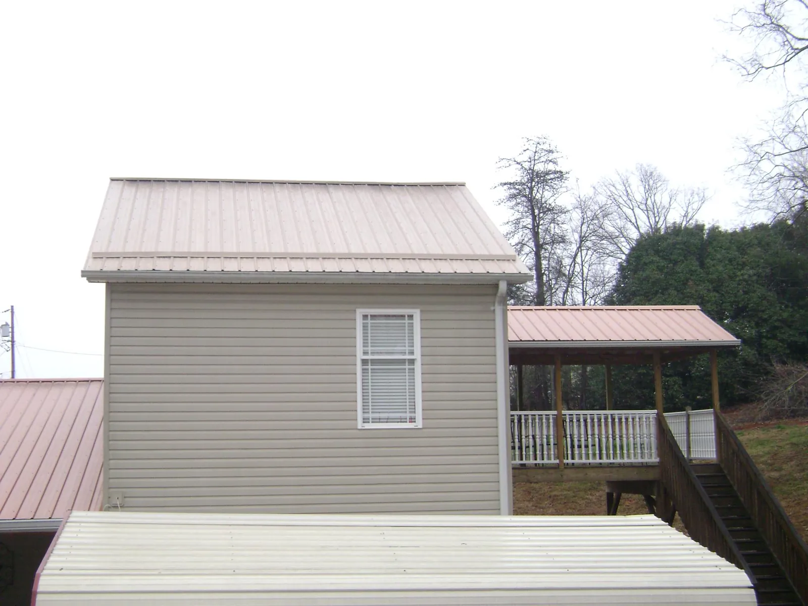 Tan metal roofs on a two story addition and attached porch, from a Roof Replacement job in Orangevale