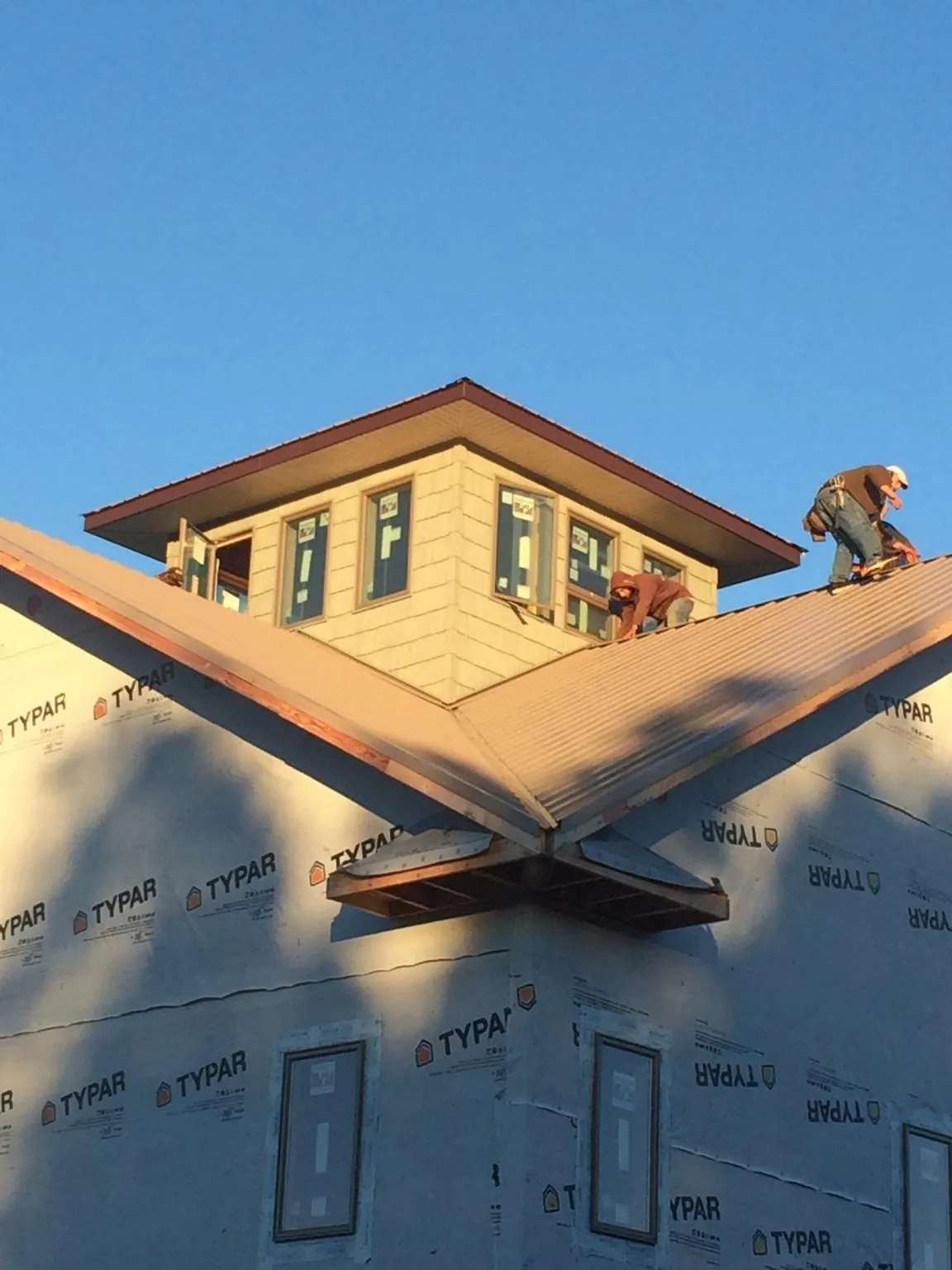 Roofers working around a rooftop cupola on a new metal roof at sunset — Roof Waterproofing in Orangevale by Roofing Brothers